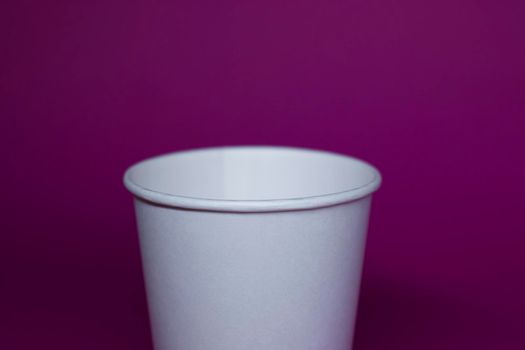 An empty white paper cup on a pink background. horizontal photo.