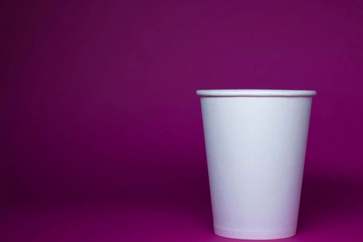 An empty white paper cup on a pink background. horizontal photo.