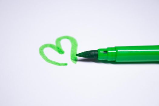 green felt-tip pen with a painted heart next to it. stationery concept. copy space. isolated. High quality photo