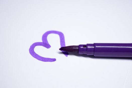 purple felt-tip pen with a painted heart next to it. stationery concept. copy space. isolated. High quality photo