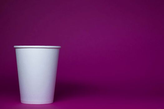 An empty white paper cup on a pink background. horizontal photo.