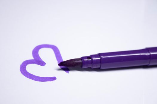 purple felt-tip pen with a painted heart next to it. stationery concept. copy space. isolated. High quality photo