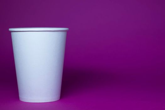 An empty white paper cup on a pink background. horizontal photo.