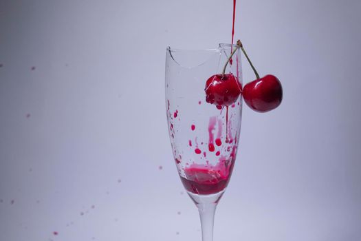 drops of red liquid - blood - in a broken champagne glass with a cherry on it on a white background. Isolated. Copy space. pain concept. High quality photo