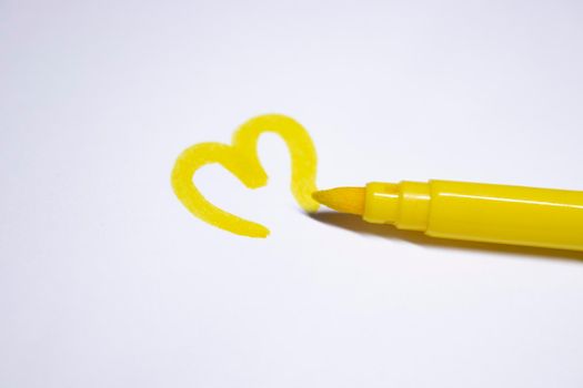 yellow felt-tip pen with a painted heart next to it. stationery concept. copy space. isolated. High quality photo