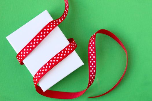 Small Christmas gift box and ribbon on green background