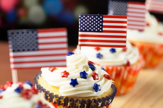 Close up of patriotic cup cake with red white and blue star topping and American flag. Shallow depth of field.