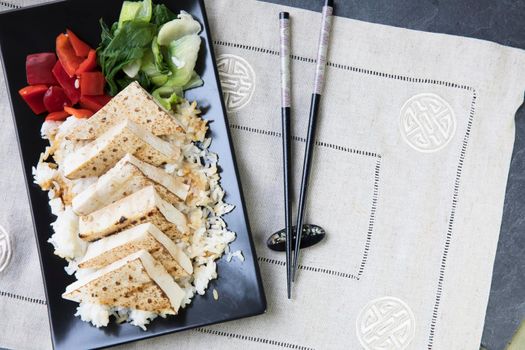 Grilled tofu on a bed of rice with red peppers and bok choy, flat lay