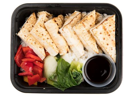Take away containter of grilled tofu on a bed of rice with red peppers and bok choy; isolated on white and top view