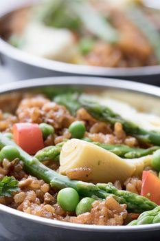 Healthy bowl of vegan paella with asparagus, mushrooms and artichoke hearts.