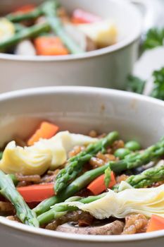 Healthy bowl of vegan paella with asparagus, mushrooms and artichoke hearts.