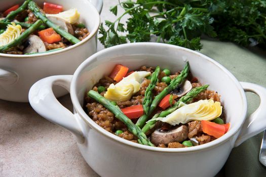 Healthy bowl of vegan paella with asparagus, mushrooms and artichoke hearts.