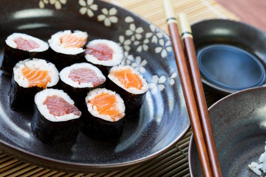 Tuna and salmon maki rolls with soy sauce and chop sticks.