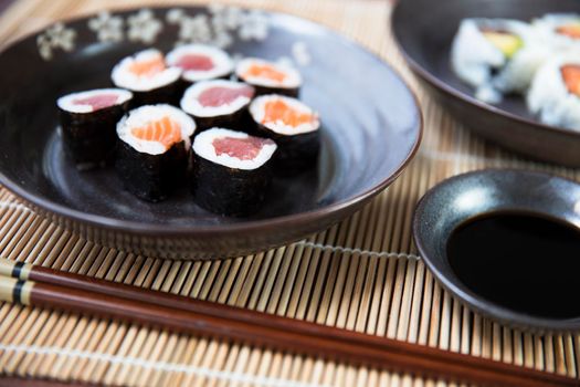 Tuna and salmon maki rolls with soy sauce and chop sticks.