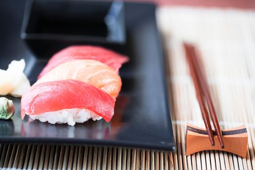 Salmon and tuna nigiri rolls with ginger, wasabi, and chop sticks.