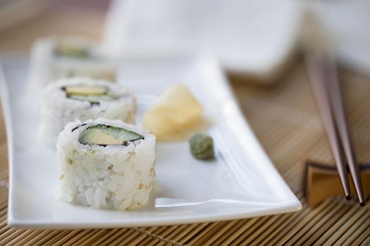 Vegan cucumber and avocado uramaki sushi rolls with wasabi and pickled ginger.