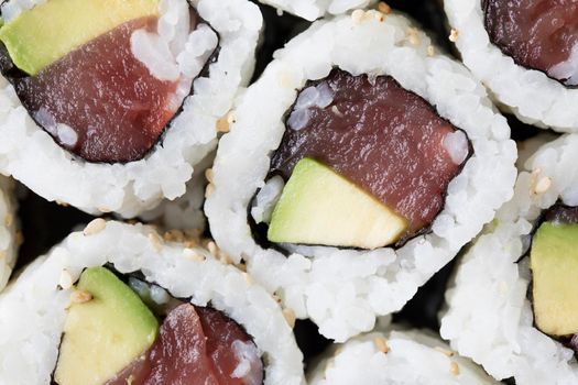Fresh tuna and avocado uramaki sushi rolls close up and top view.