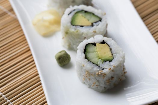 Vegan cucumber and avocado uramaki sushi rolls with wasabi and pickled ginger.