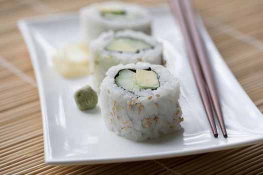Vegan cucumber and avocado uramaki sushi rolls with wasabi and pickled ginger.