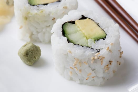 Vegan cucumber and avocado uramaki sushi rolls with wasabi.