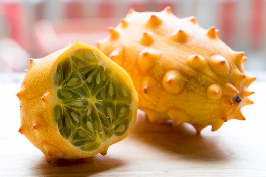 Whole and cut kiwano fruit on cutting board.