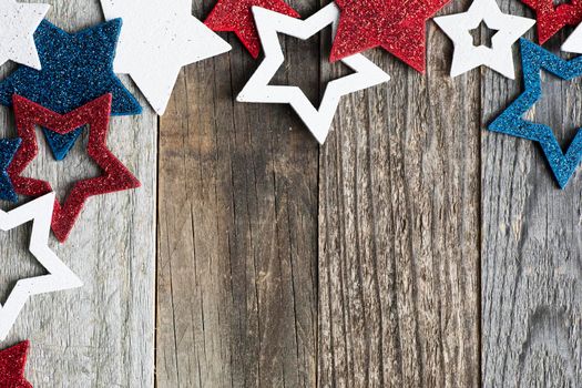 Red white and blue glittery star decorations on wooden surface with copy space.