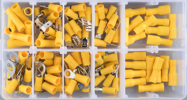 Yellow electric terminal connectors organized in plastic contaner.