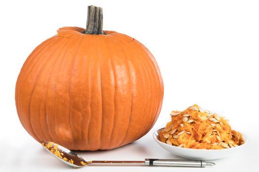 Recently cleaned pumpkin with seeds in bowl and large spoon, ready for carving