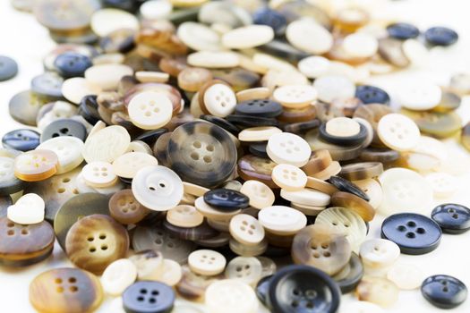 Pile of buttons in browns, white and black tones.