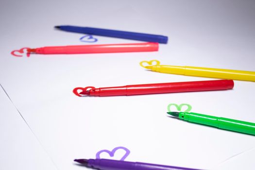 multicoloured felt-tip pen with a painted heart next to it. stationery concept. copy space. isolated. High quality photo