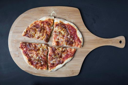 Fresh cheese and ham pizza slices on pizza peel.