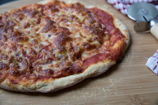 Close Up of whole homemade cheese and ham pizza with pizza wheel.