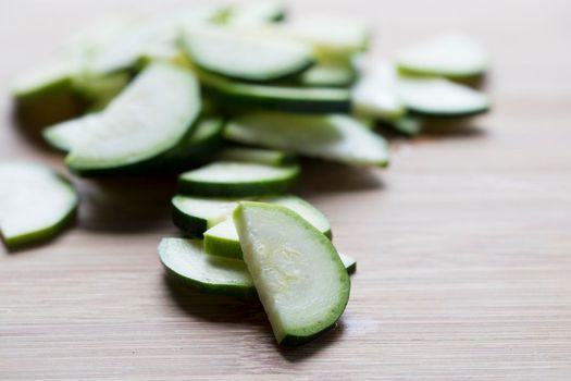 Thin slices of zucchini half on wooden cutting surface