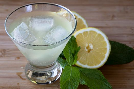 Lemon cocktail with half lemon and mint on table