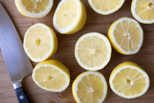 Fresh sliced lemon halves on cutting surface with chef's knife.