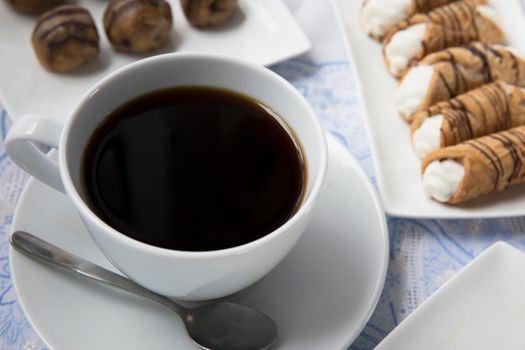 Cup of fresh coffee with chocolates and pastries