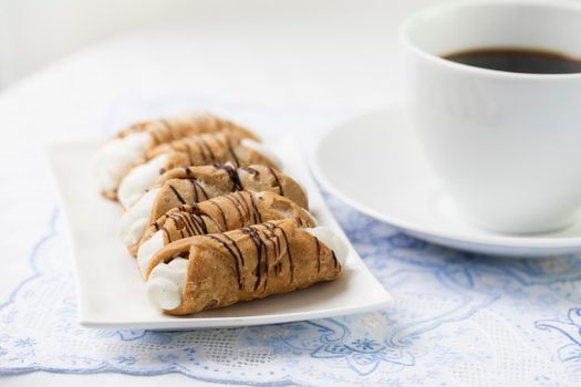 Pastries Stuffed with sweet cream and drizzled with chocolate served with coffee.