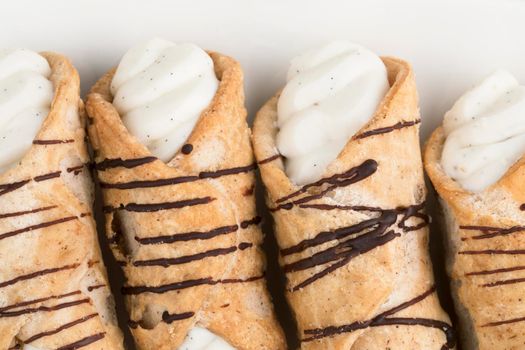 Close up of pastries stuffed with sweet cream and drizzled with chocolate, viewed from avove