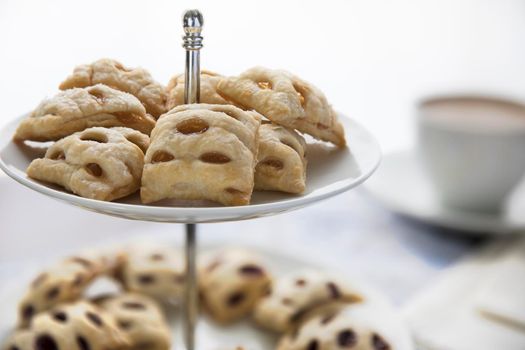 Fruit filled mini strudels on pastry stand with coffee or tea in the background