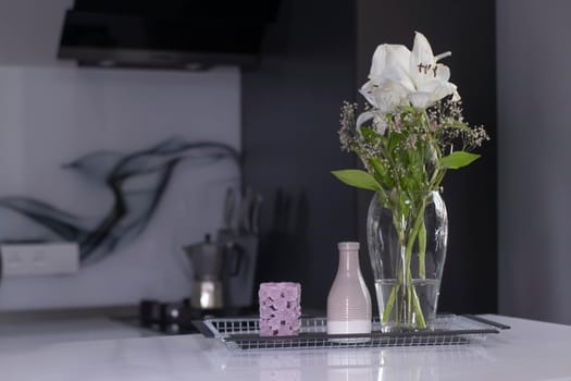 set of home decoration - candle, vase and flowers - on a handmade black metal tray at the kitchen. home interior and decor concept. High quality photo