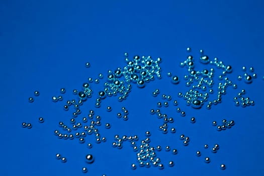 A lot of silver little balls on a blue background. Horizontal photo