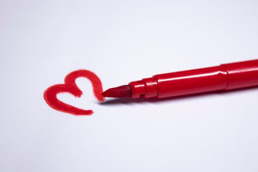 red felt-tip pen with a painted heart next to it. stationery concept. copy space. isolated. High quality photo