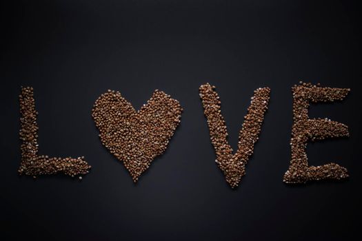 Words 'LOVE' written with buckwheat On gray background, top view, copy space. Food supplies crisis, food donation on quarantine isolation period.