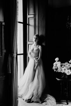 Bride is leaning against the frame of the large window of an old villa. Lake Como. Black and white photo. High quality photo