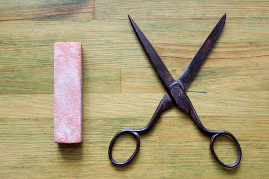 vintage scissors and red grindstone on the  green  wooden background