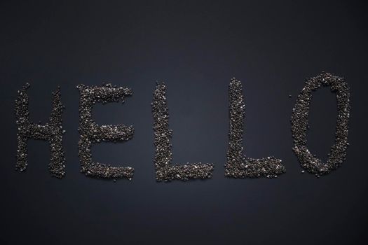 Word 'HELLO' written with chia seeds on gray background, top view, copy space.