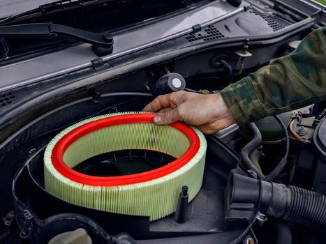 Man replaced air filter on engine of car.