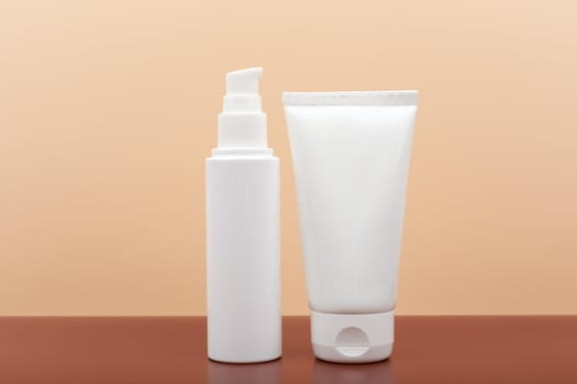 Two white cream tubes on brown table against beige background. Concept of skin care and beauty
