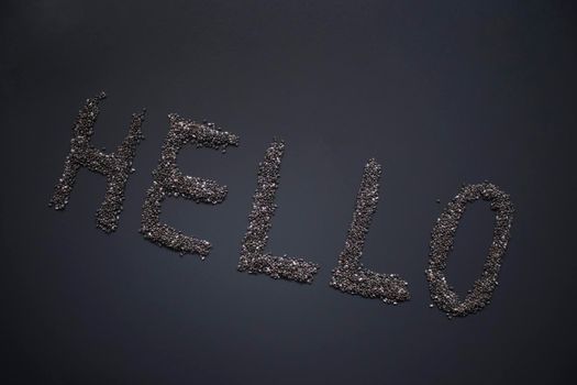 Word 'HELLO' written with chia seeds on gray background, top view, copy space.