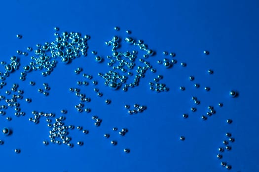 A lot of silver little balls on a blue background. Horizontal photo